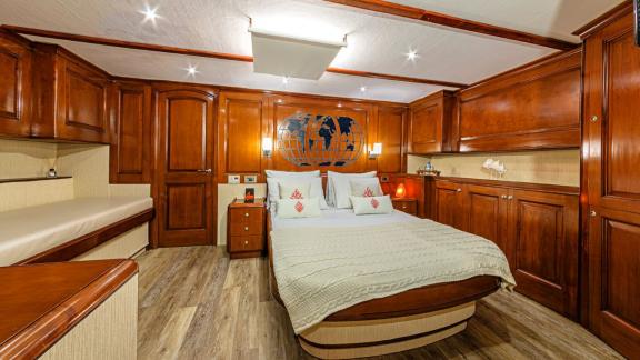 Luxurious cabin with wood panelling, large bed, sofa and stylish lighting.